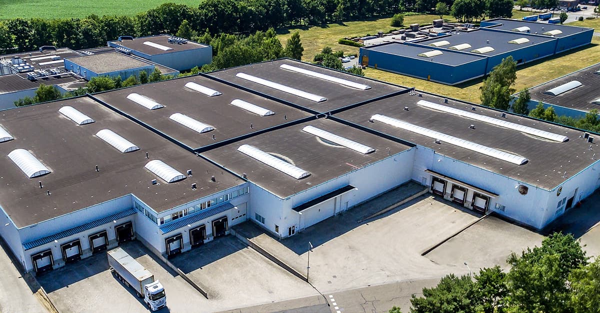 Aerial view of an industrial warehouse complex with multiple buildings, loading docks, and surrounding greenery.