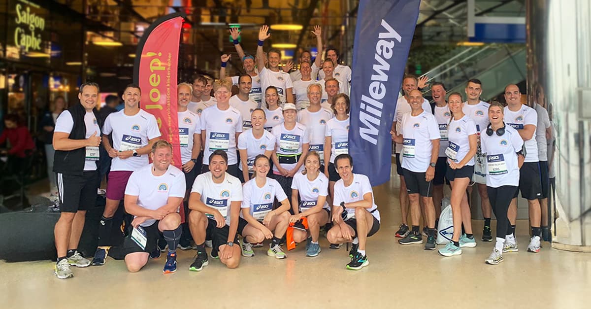 A group of people in matching athletic wear pose together indoors, surrounded by colorful banners.