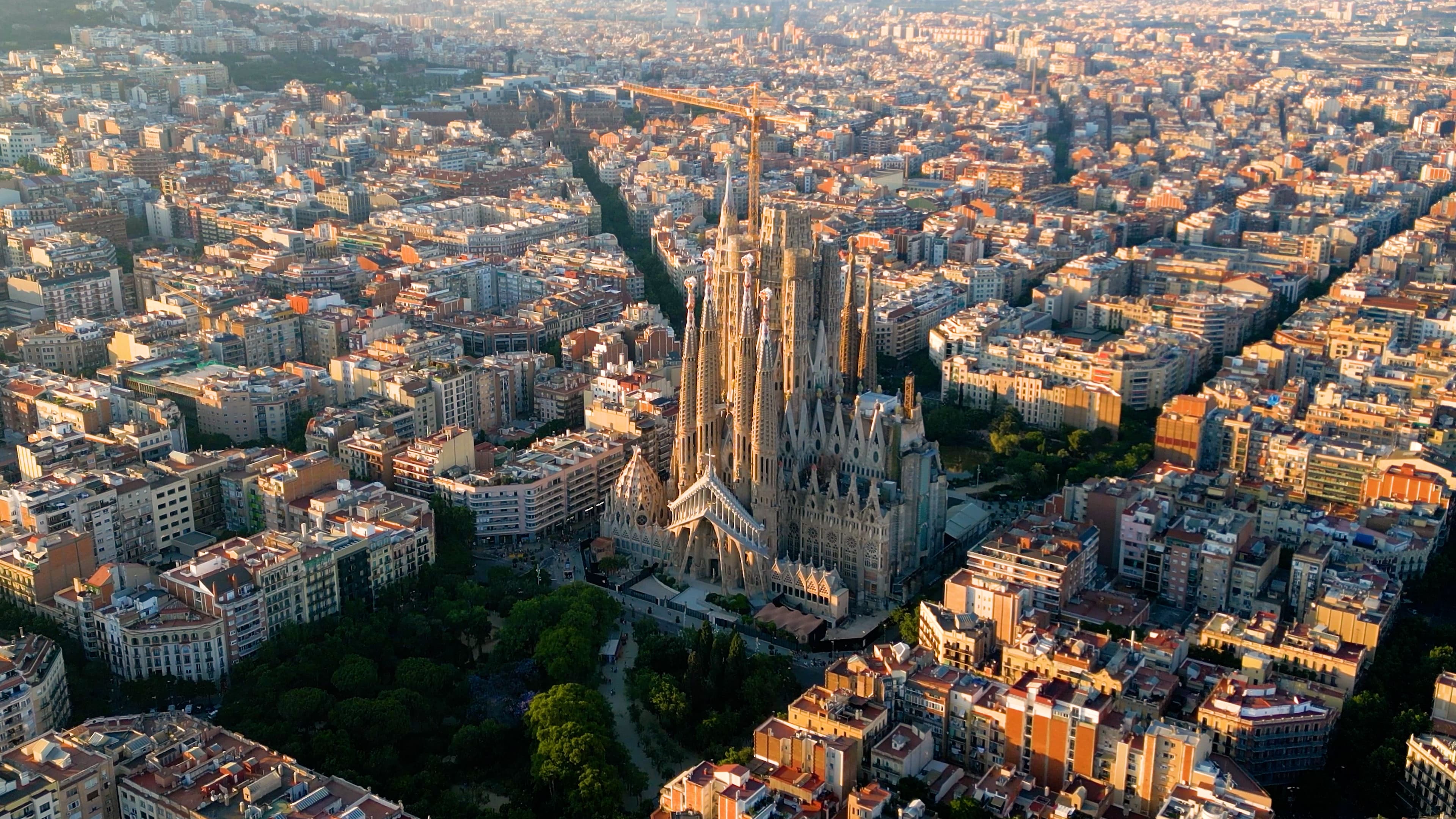 Aerial view of the Sagrada Familia in Barcelona, surrounded by a grid-like pattern of city buildings.
