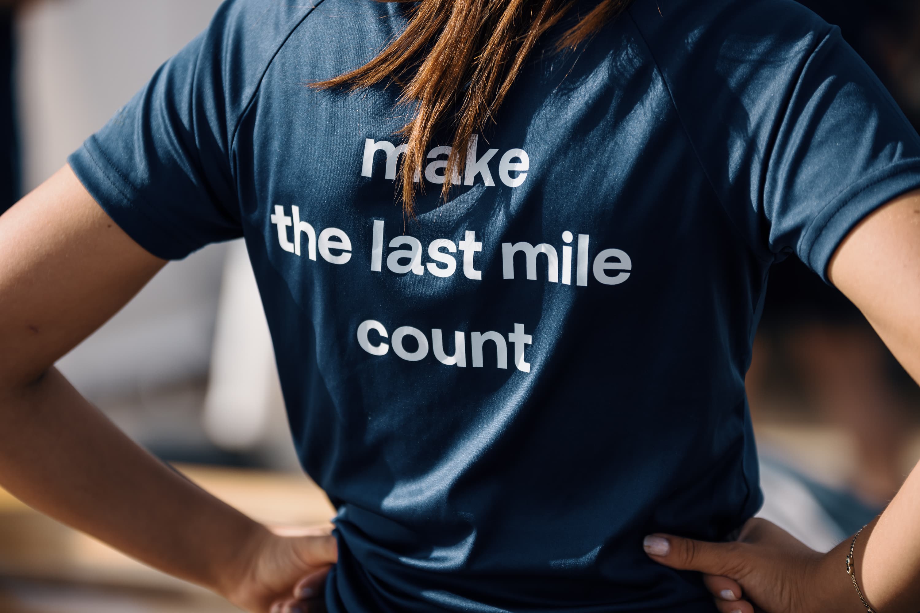 Person wearing a navy t-shirt with the text make the last mile count printed on the back.