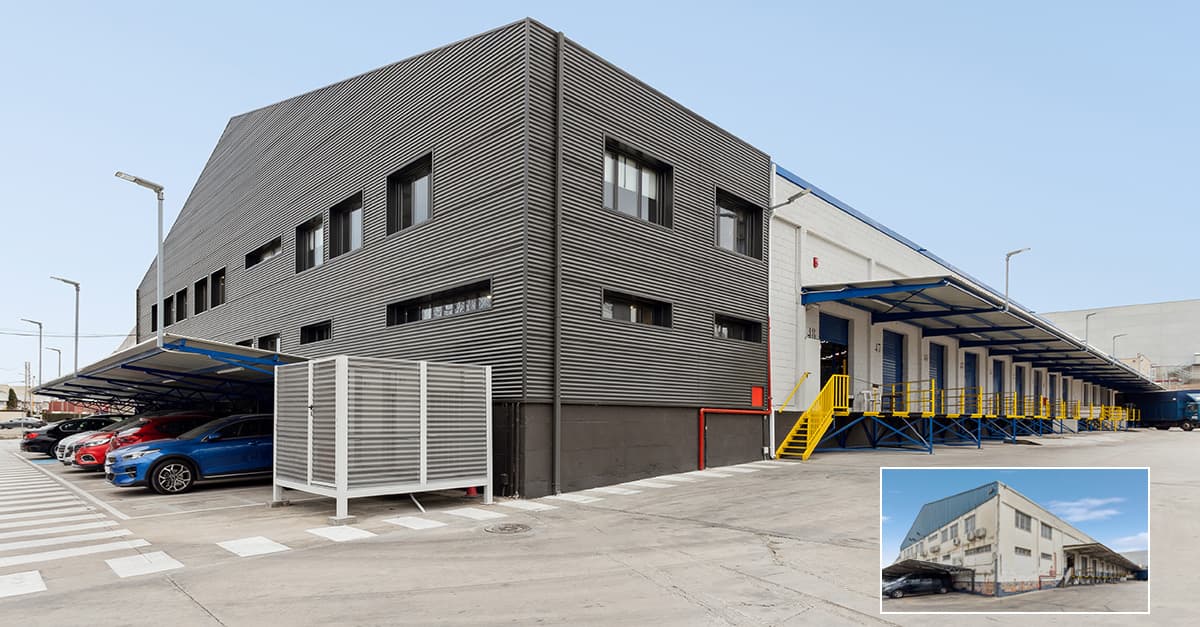 A modern industrial building with gray corrugated metal siding, loading docks, and parked cars. An inset shows a previous version of the same building.