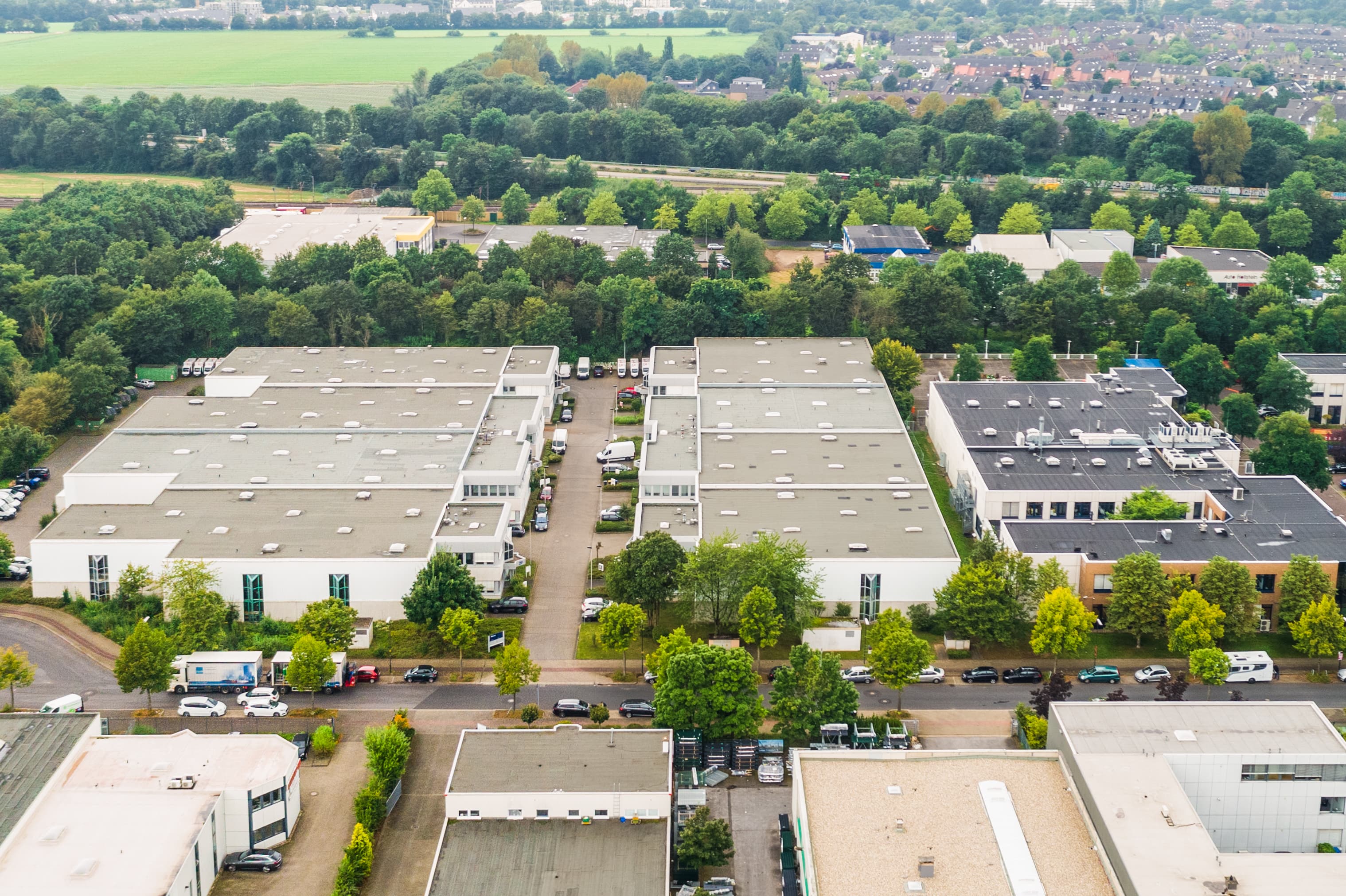 Aerial view of an industrial area with multiple large warehouses, surrounded by trees and roads.