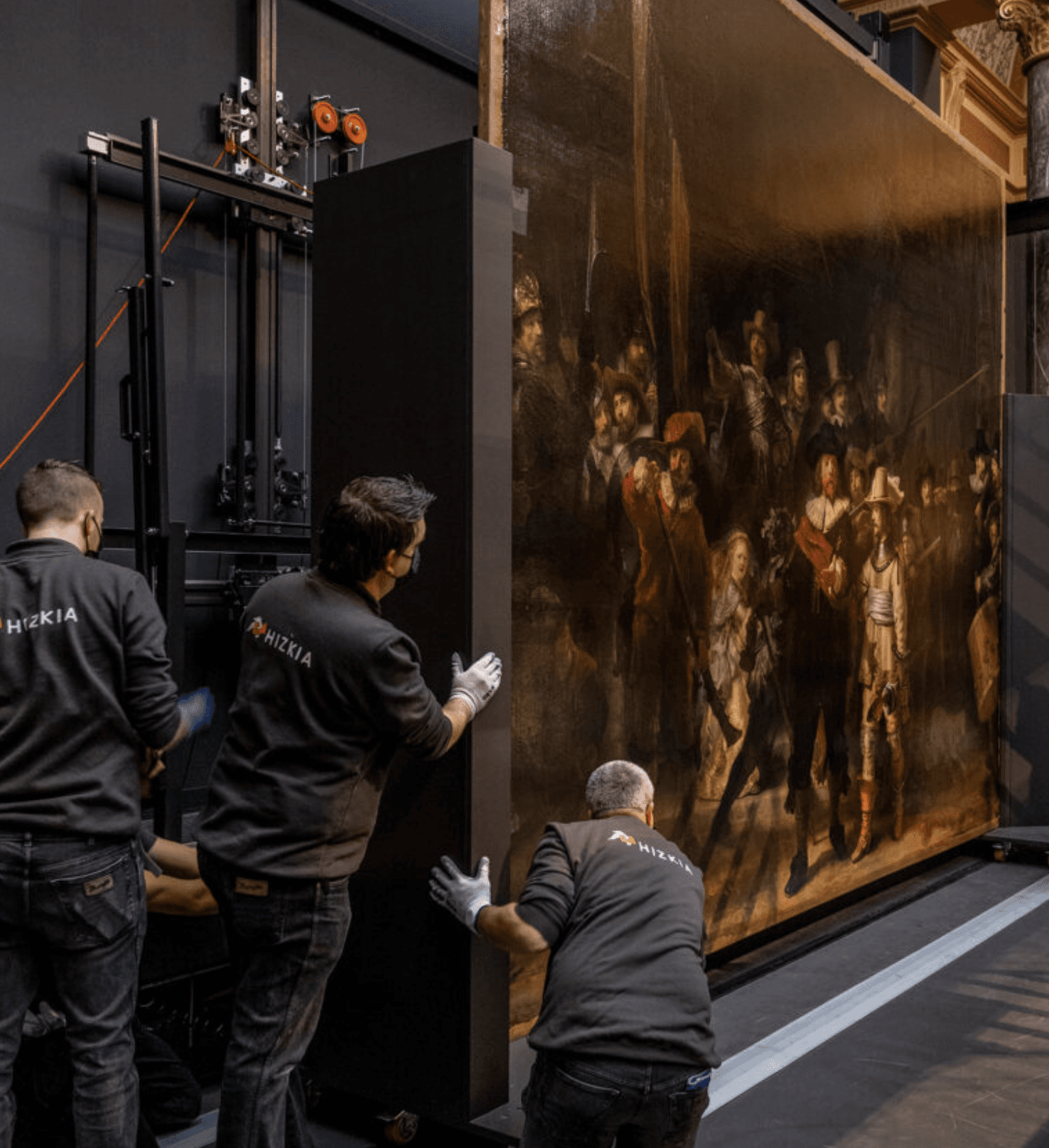 Workers carefully move a large, framed painting using a specialized lift.