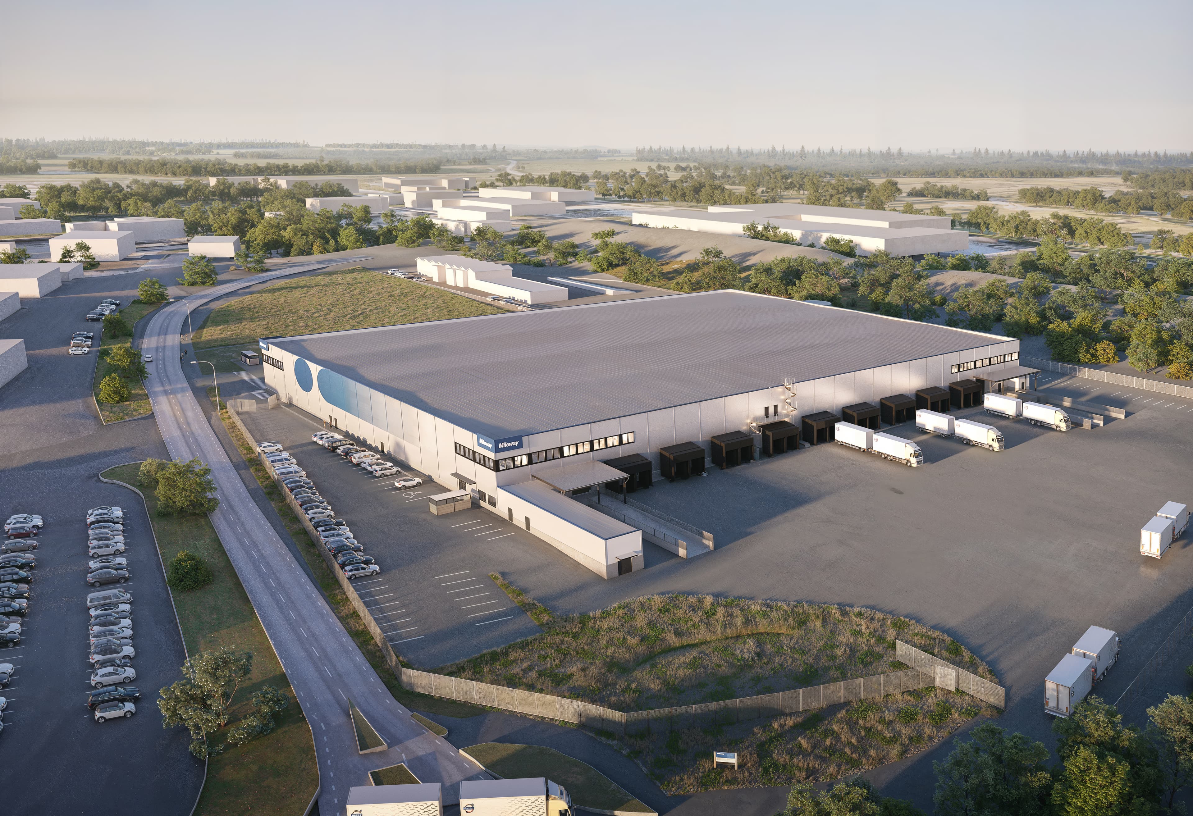 Aerial view of a large warehouse with several loading docks and parked trucks, surrounded by parking lots and greenery.