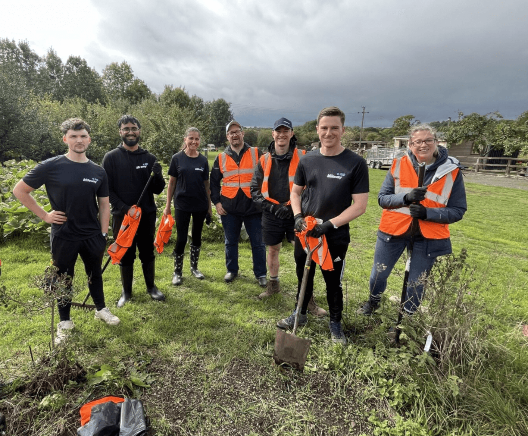 A group of people in orange vests and orange vests standing in a circle.
